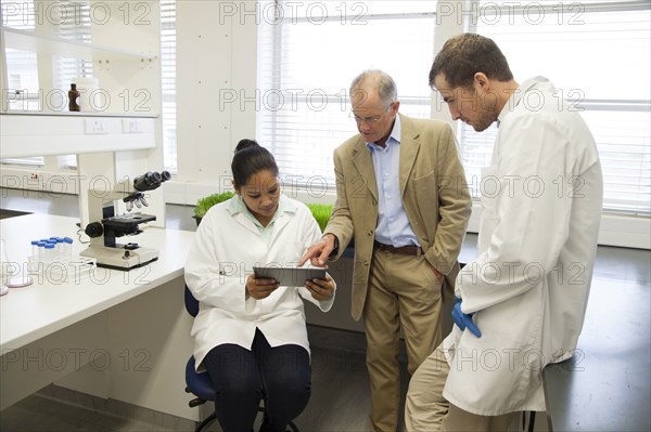 Businessman and scientists using digital tablet in laboratory