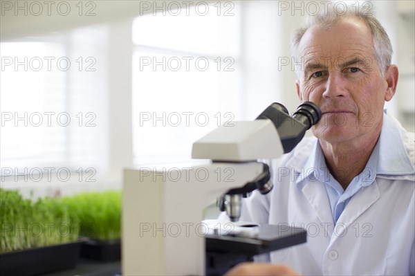 Caucasian scientist using microscope in laboratory