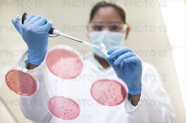 Mixed race scientist pipetting sample into test tube in laboratory