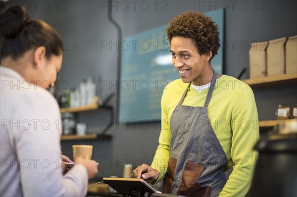 Mixed race barista assisting customer in coffee shop