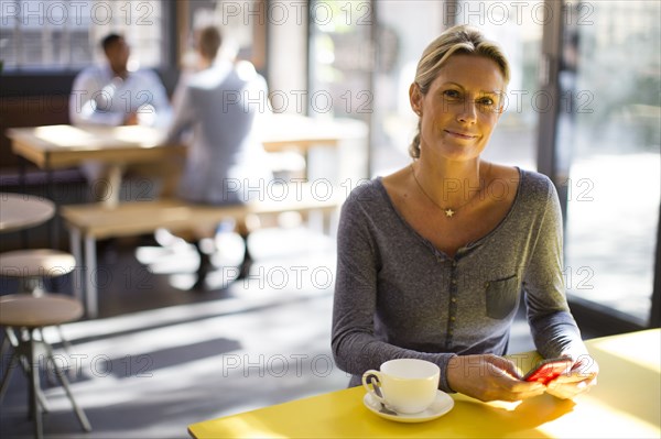 Woman using cell phone in cafe