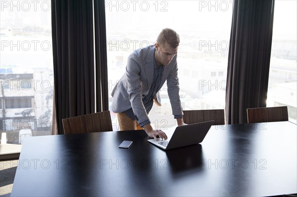 Caucasian businessman using laptop in conference room