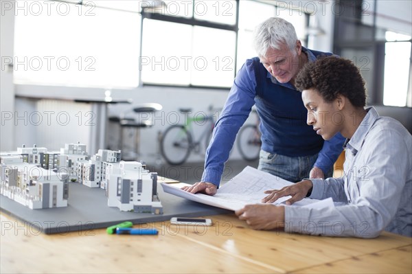 Architects examining architectural model in office