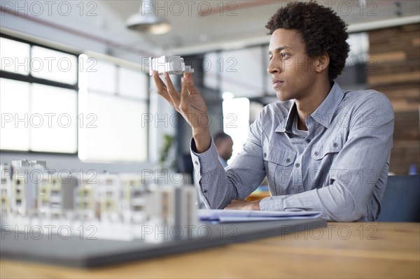 Mixed race architect examining architectural model in office