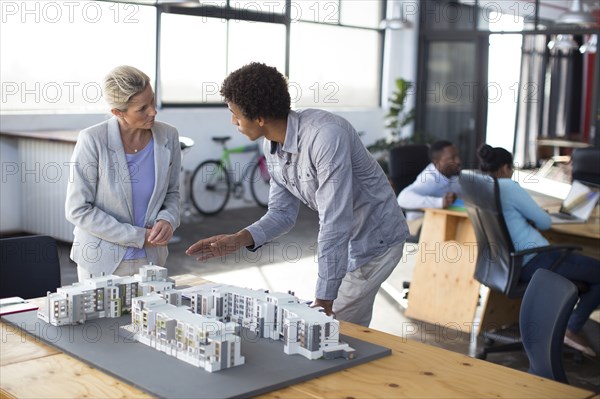 Architects examining architectural model in office