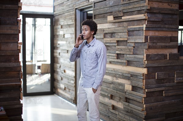 Mixed race businessman talking on cell phone in hallway