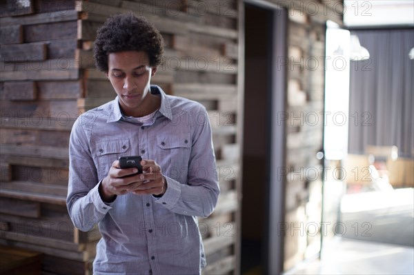 Mixed race businessman using cell phone in hallway