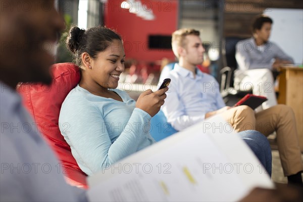 Businesswoman using cell phone in office lounge