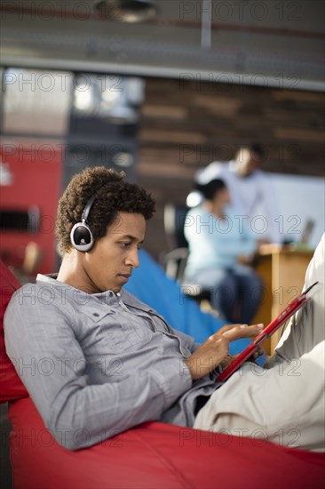 Mixed race businessman using digital tablet in office lounge