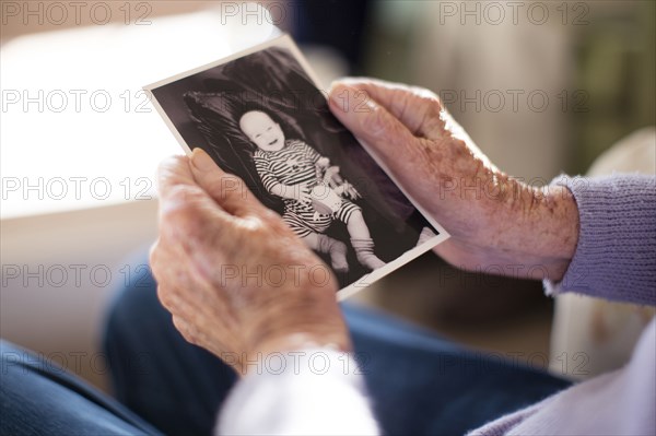 Caucasian woman admiring photograph of baby