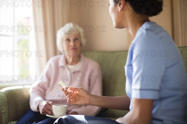Nurse and patient drinking tea on sofa