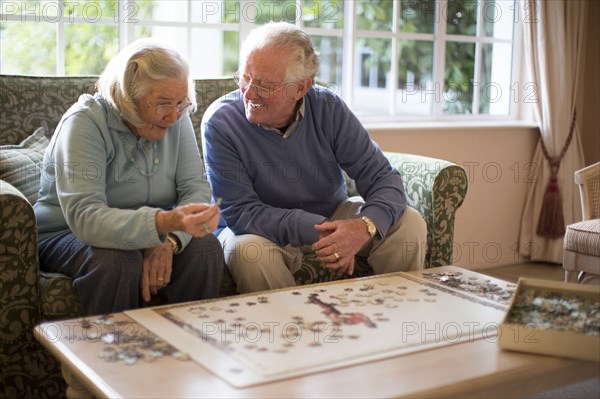 Older couple on sofa solving jigsaw puzzle