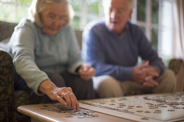 Older couple on sofa solving jigsaw puzzle