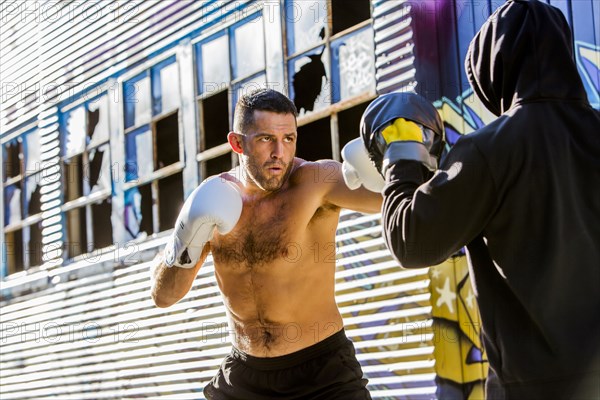 Caucasian boxer sparring with trainer