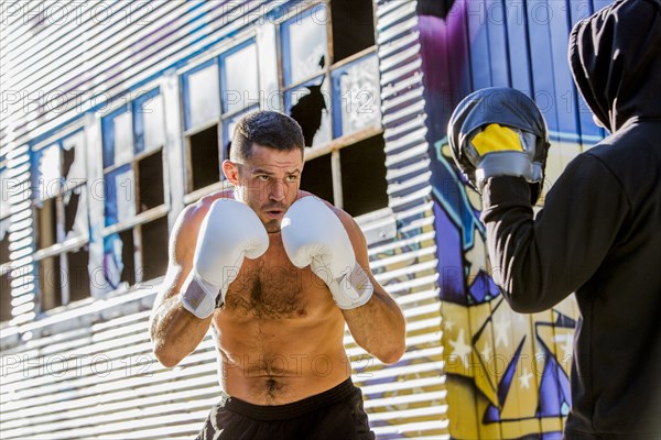 Caucasian boxer sparring with trainer