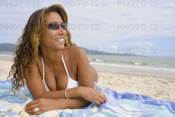 Hispanic woman lying on the beach