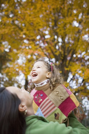 Mother and young daughter laughing outdoors