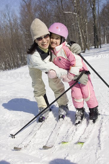 Mother and daughter smiling on skis