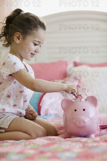 Young girl putting money in piggy bank