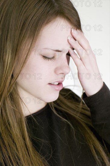 Young woman touching forehead with eyes closed