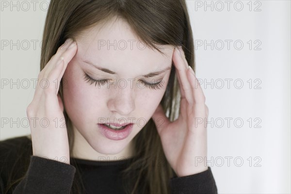 Studio shot of young woman rubbing temples