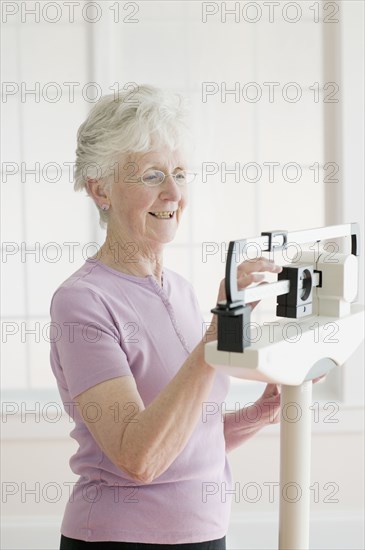 Senior woman weighing self on scale