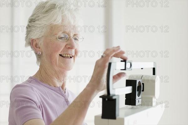 Senior woman weighing self on scale