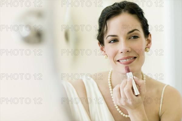 Woman in fancy clothing applying lipstick