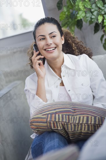 Dominican woman talking on cell phone on sofa