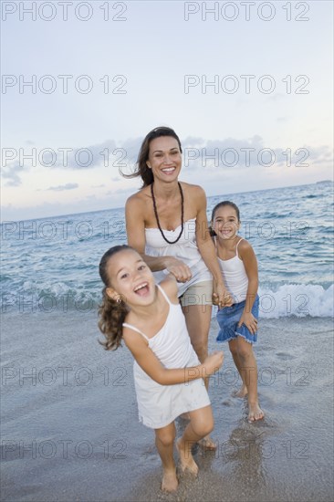 Multi-ethnic mother and daughters playing in surf