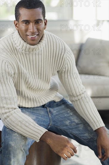 Indian man sitting on edge of sofa