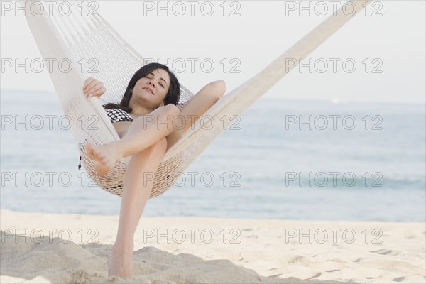 Cuban woman laying in hammock on beach