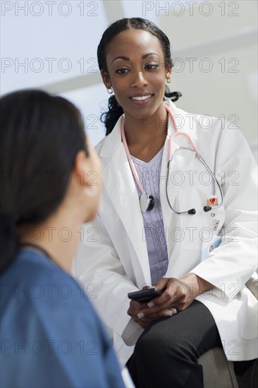 Doctor with cell phone talking to co-worker