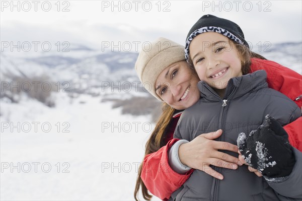Hispanic mother hugging son in snow field