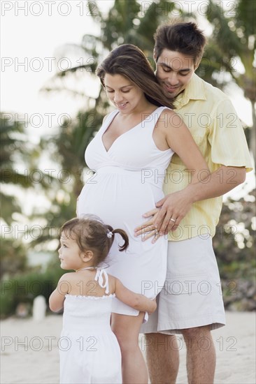 Husband hugging pregnant wife and watching daughter