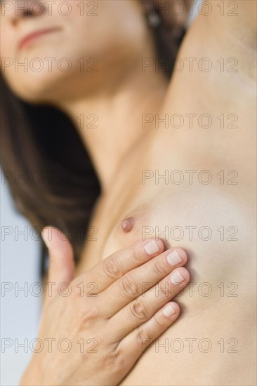 Close up of Hispanic woman doing breast self-exam