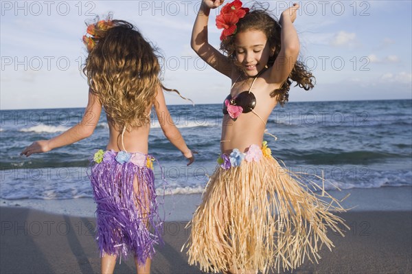Hispanic girls dancing in hula skirts on beach
