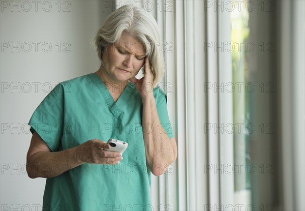 Caucasian surgeon in scrubs using cell phone