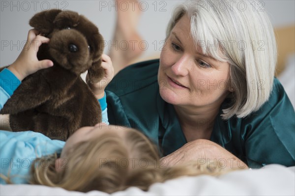 Caucasian grandmother laying on bed with granddaughter