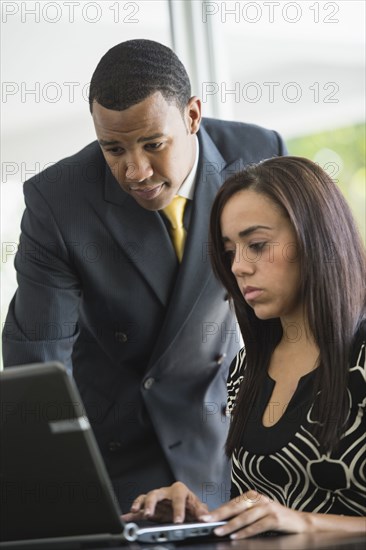 Mixed race business people looking at laptop