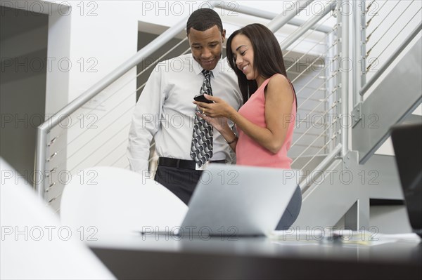 Mixed race business people looking at cell phone