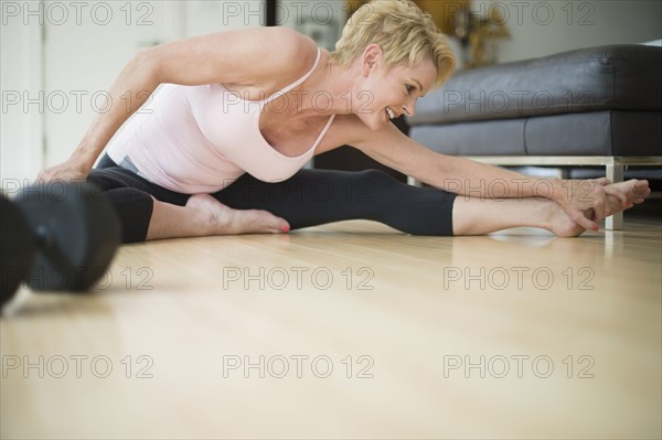 Caucasian woman stretching on floor