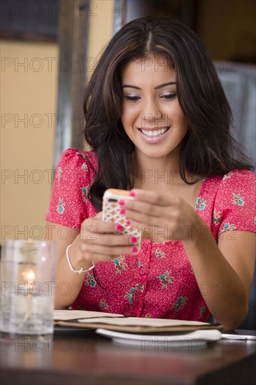 Hispanic woman using cell phone in restaurant