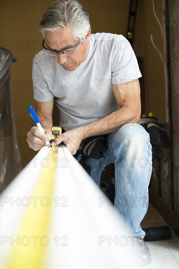 Caucasian man measuring wood