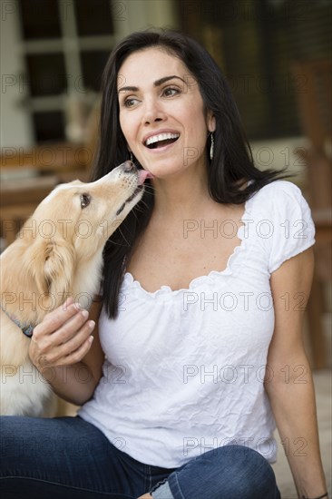 Hispanic woman playing with dog