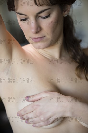 Nude Hispanic woman covering her breasts