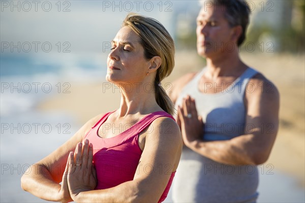 Caucasian couple meditating on beach