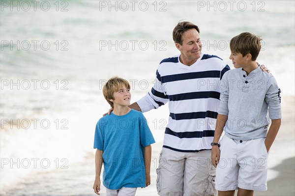 Caucasian father and sons walking on beach