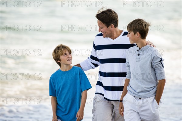 Caucasian father and sons walking on beach