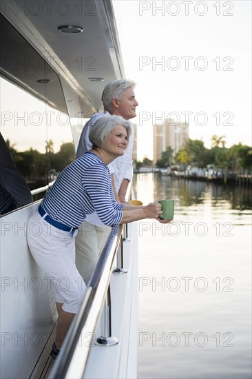 Older Caucasian couple having coffee on boat deck